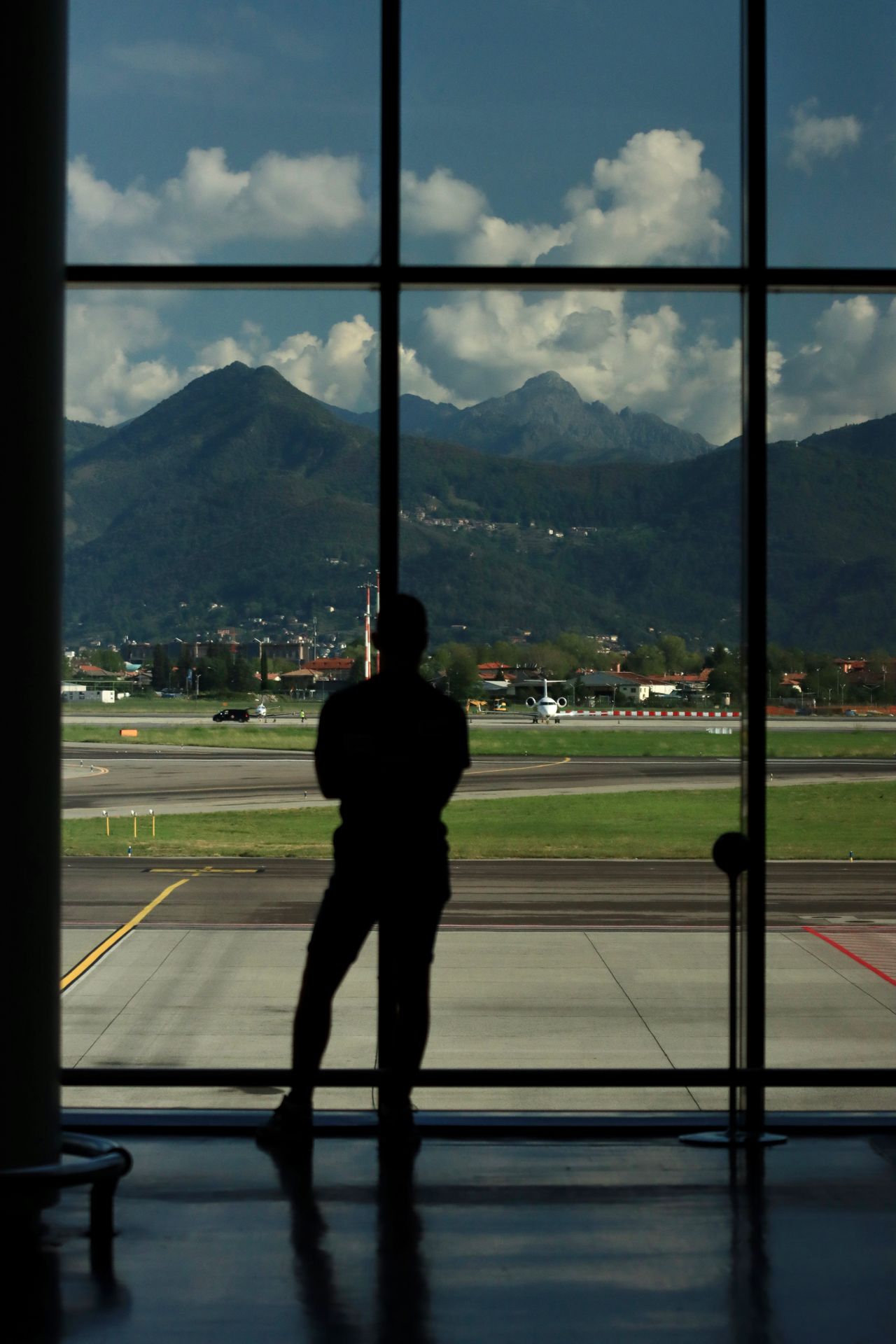 Viajante observando a pista de aeroporto com montanhas ao fundo